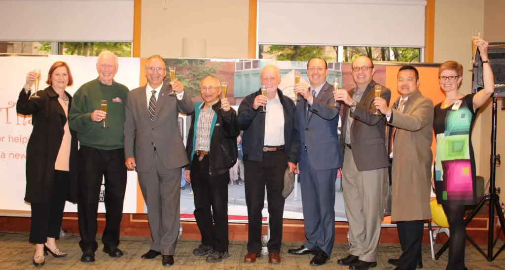Group of community leaders raising glasses for a celebratory toast during an indoor event.