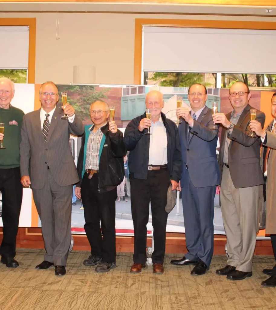 Group of community leaders raising glasses for a celebratory toast during an indoor event.